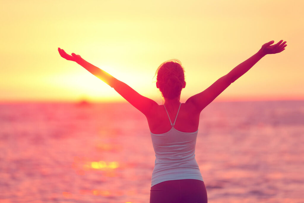 Woman with arms stretched out near sunrise and ocean. Female urinary incontinence in Washington, D.C. can feel embarrassing and shameful. You are not alone! Get support in pelvic floor physical therapy and talk with a compassionate therapist in Washington. D.C. who gets it.