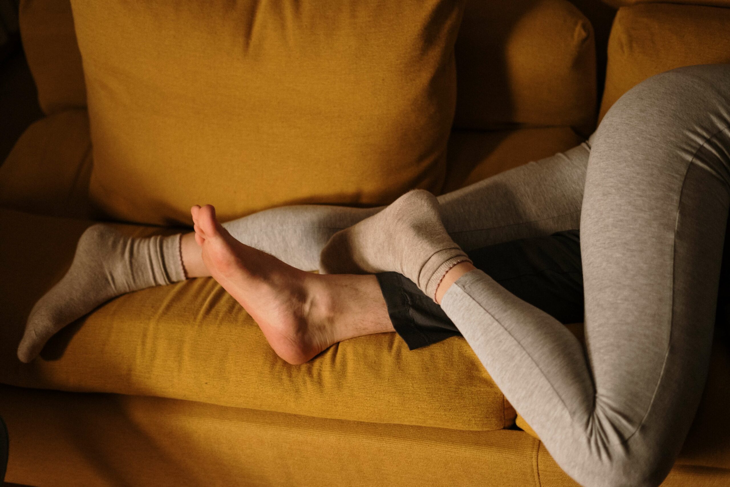 A couple lies with entwined legs on the couch representing the improved sexual function for women that can come with the help of Pelvic Floor Physical Therapy in Washington, DC.