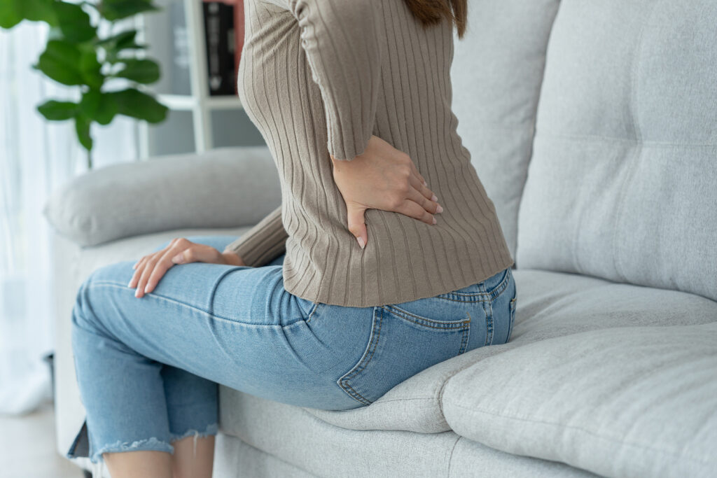 A woman experiences butt pain while sitting on her couch representing someone who could benefit from Pelvic Floor Physical Therapy in Washington, DC.