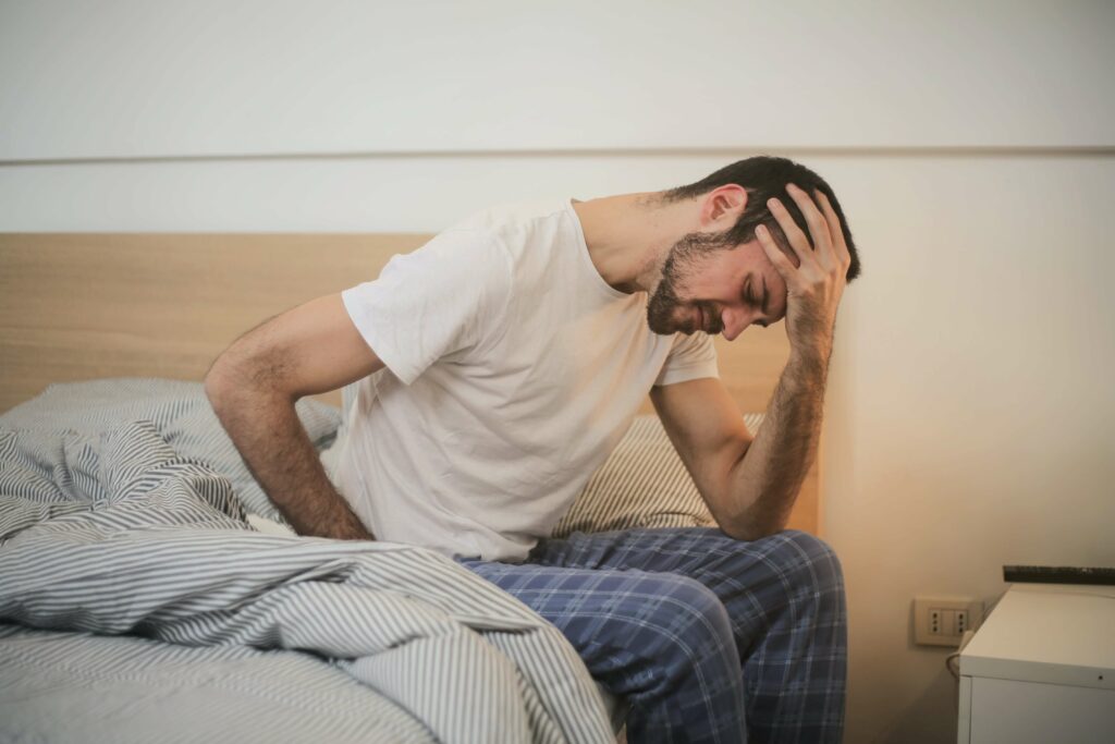A man sits on the edge of his bed with his hand resting on his hand dealing with Painful Bladder Syndrome in Washington, DC. 